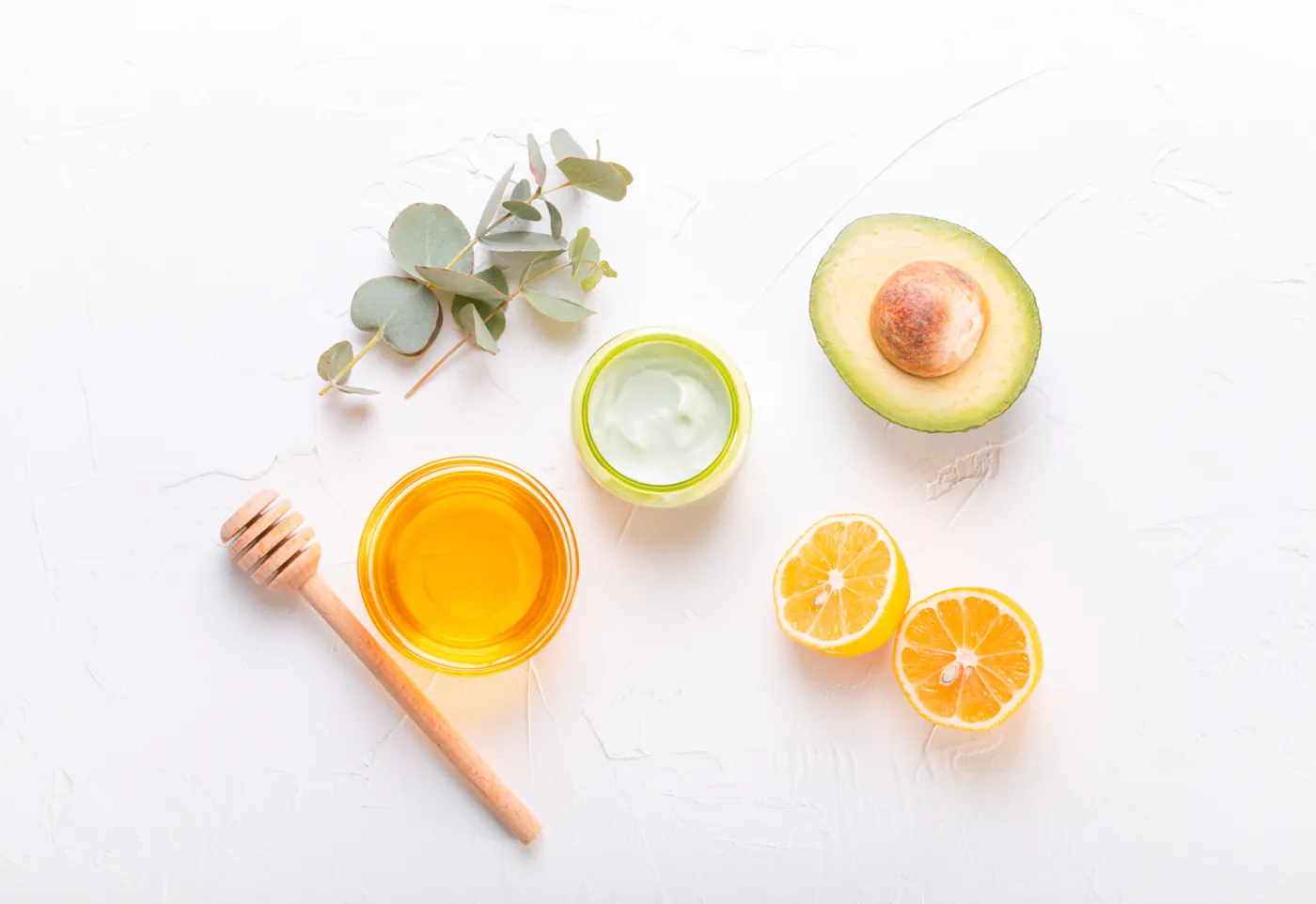 Honig, Avocado, Zitrone und Pflegeprodukte auf hellem Untergrund