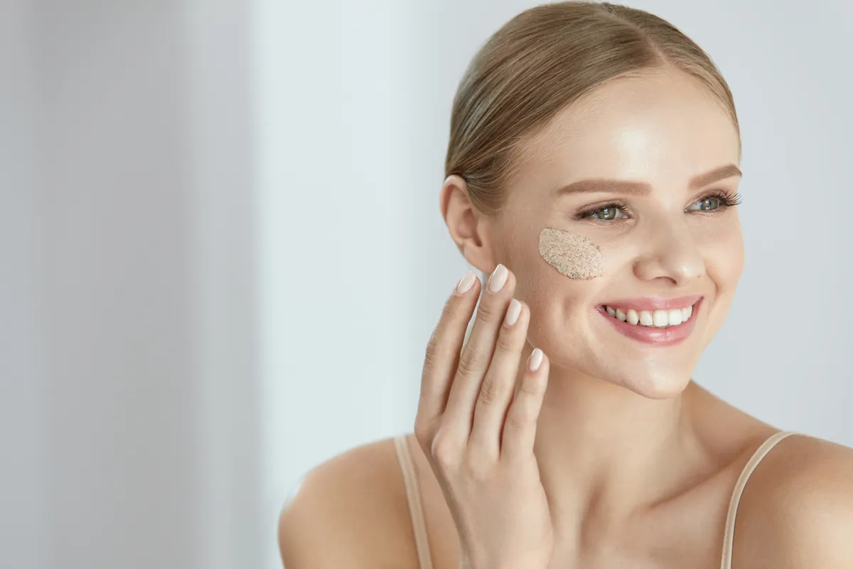 Lächelnde Frau mit Peeling auf der Wange
